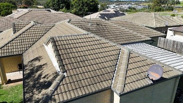 Aerial view of brown tiled rooftops in a suburban area, with a visible satellite dish.