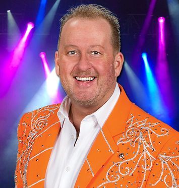 A man in an orange jacket is smiling for the camera