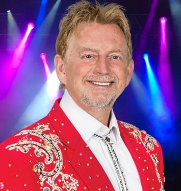 A man wearing a red jacket and tie is smiling for the camera