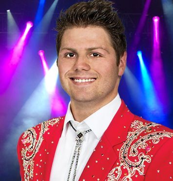 A man in a red jacket and tie smiles for the camera