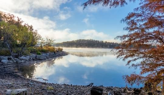 A lake surrounded by trees on a cloudy day