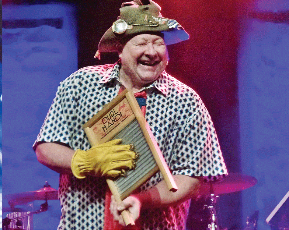 Smiling musician playing a red electric guitar on a purple-lit stage