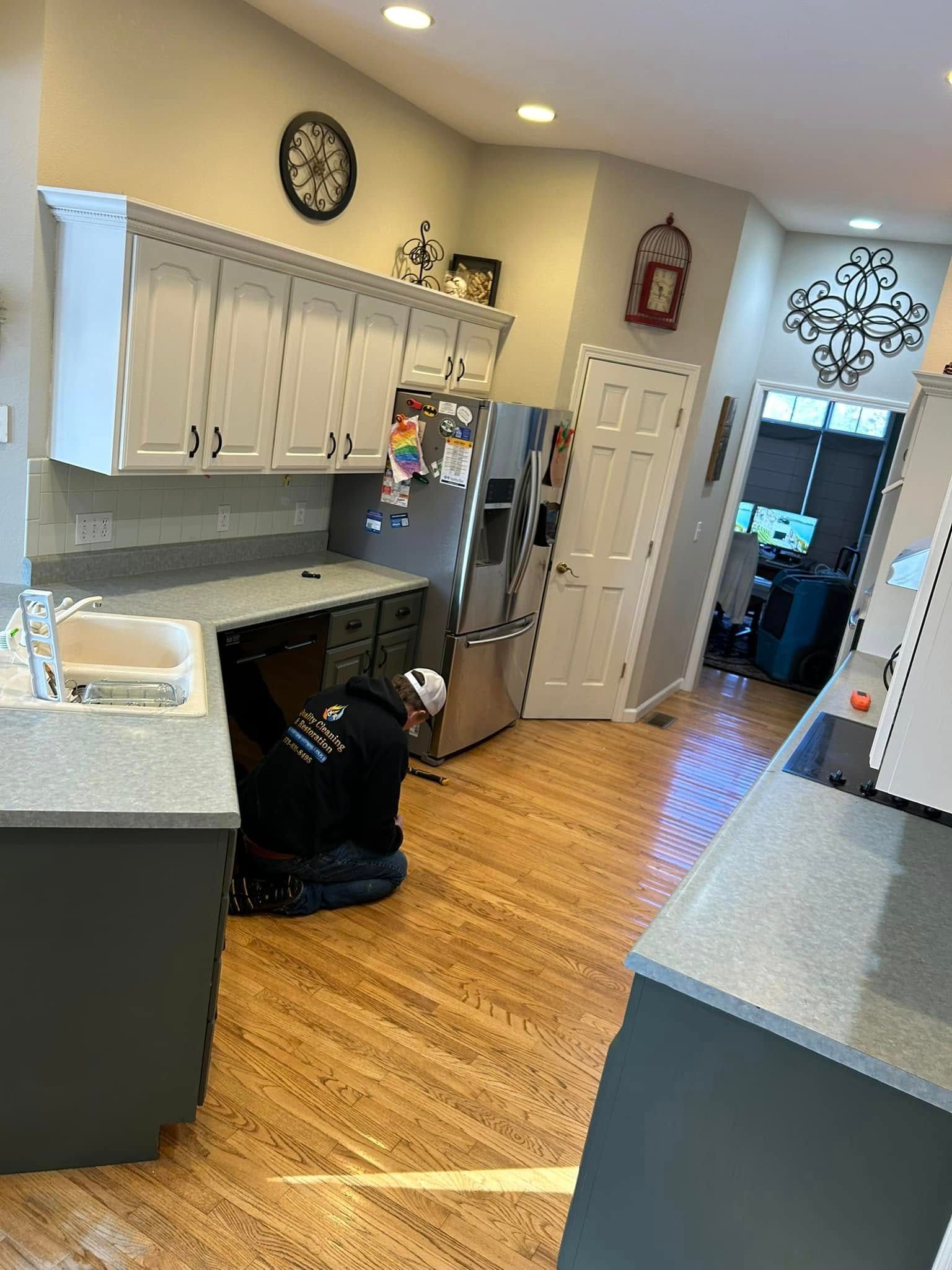Kitchen with cabinets, countertops, appliances, and a person working on the floor.