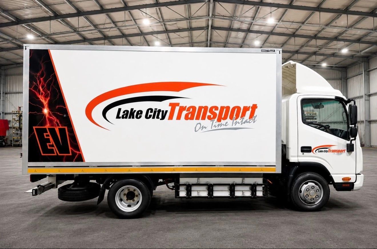 White Lake City Transport delivery truck in a warehouse, with orange and black logo on the side