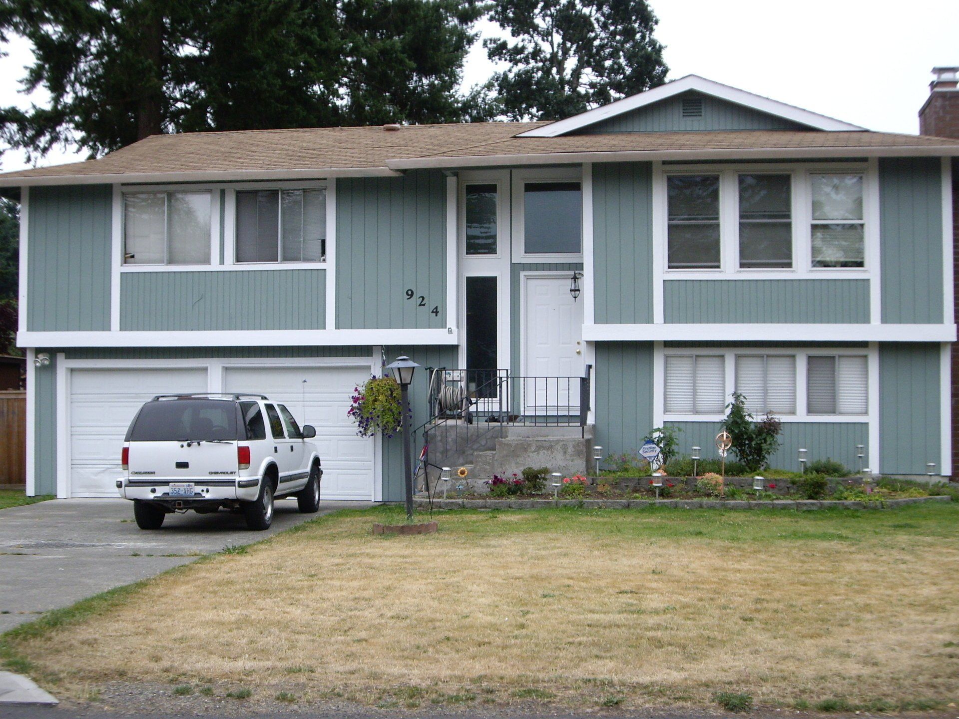 A white suv is parked in front of a house