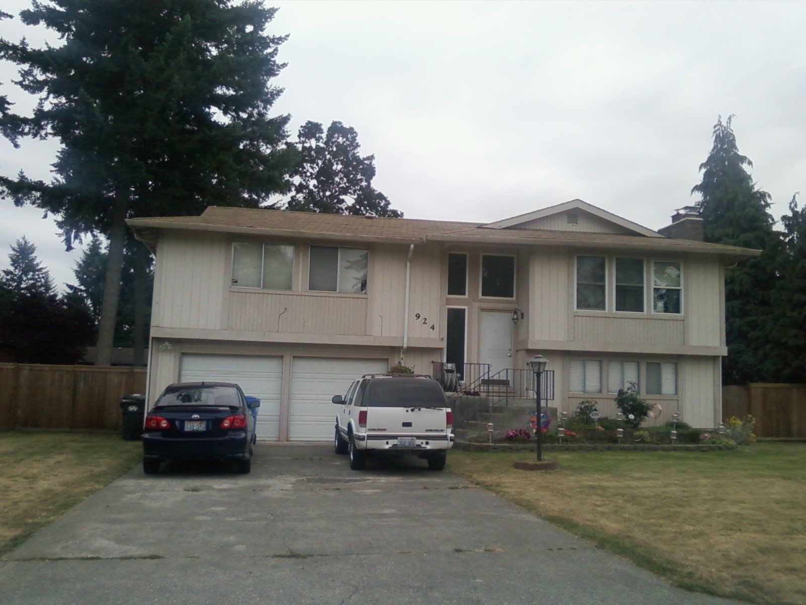 Two cars are parked in front of a large house
