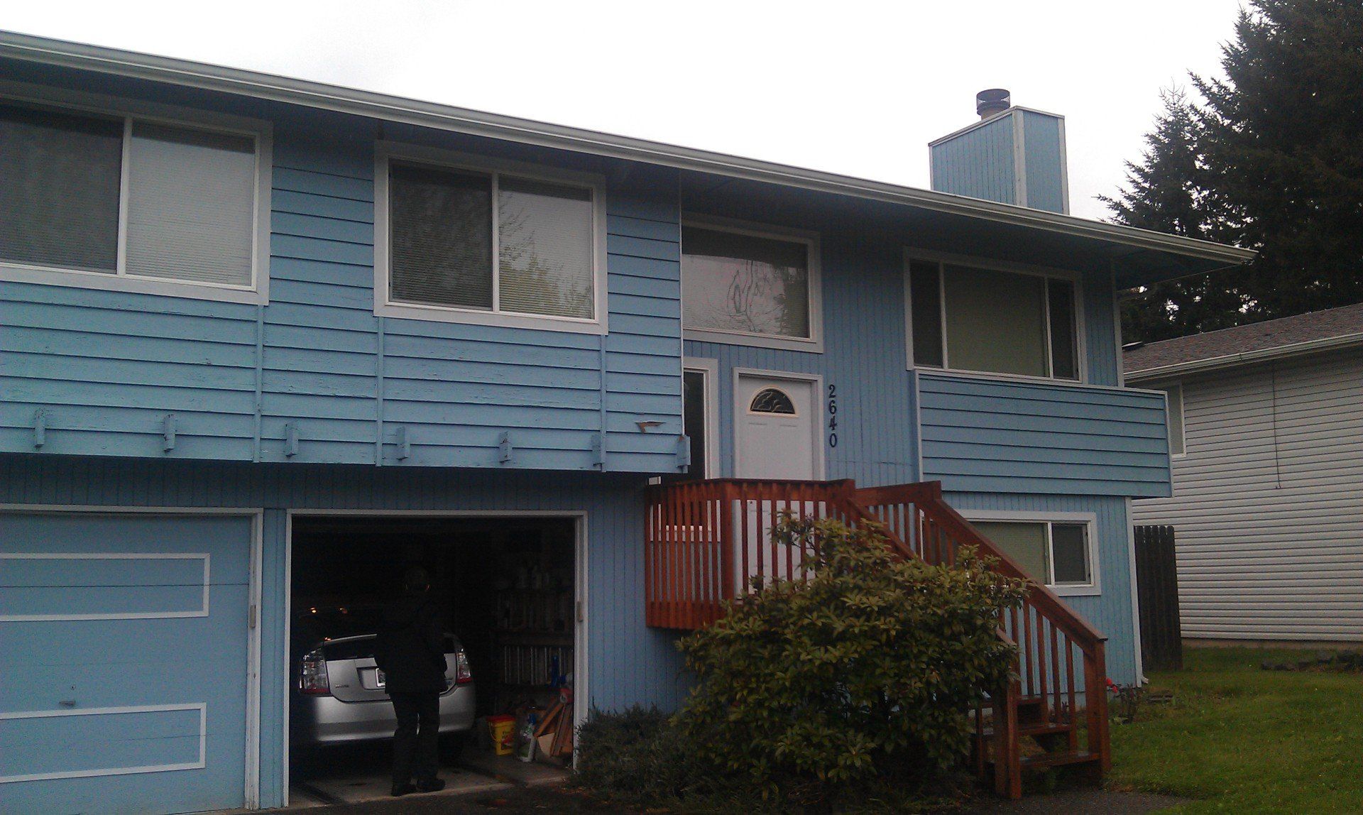 A blue house with a car parked in the garage