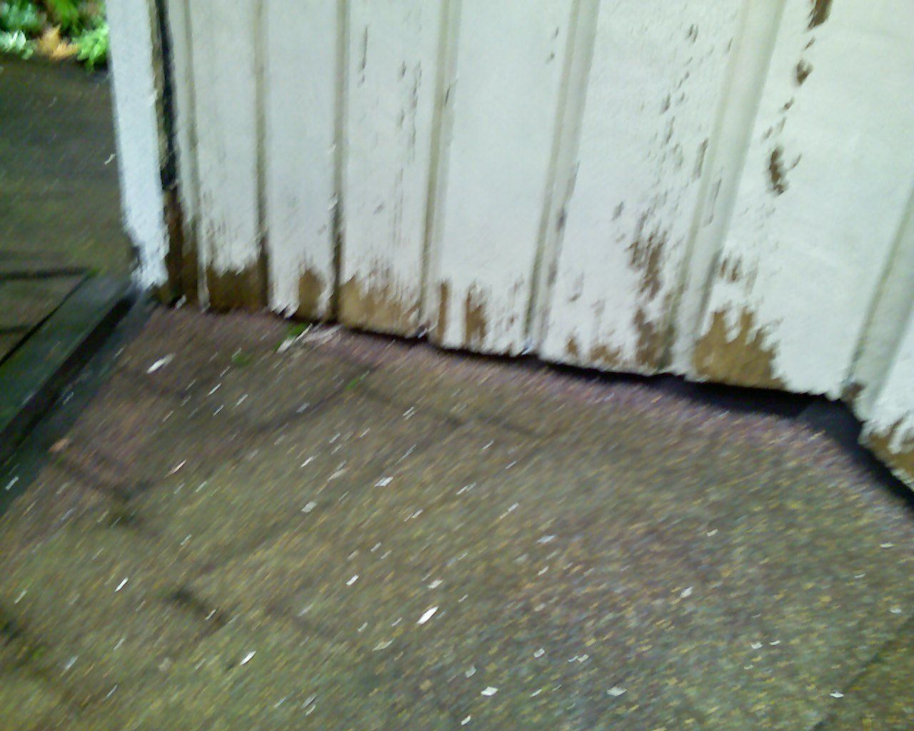 A white wall with a lot of stains on it is sitting on a concrete floor.