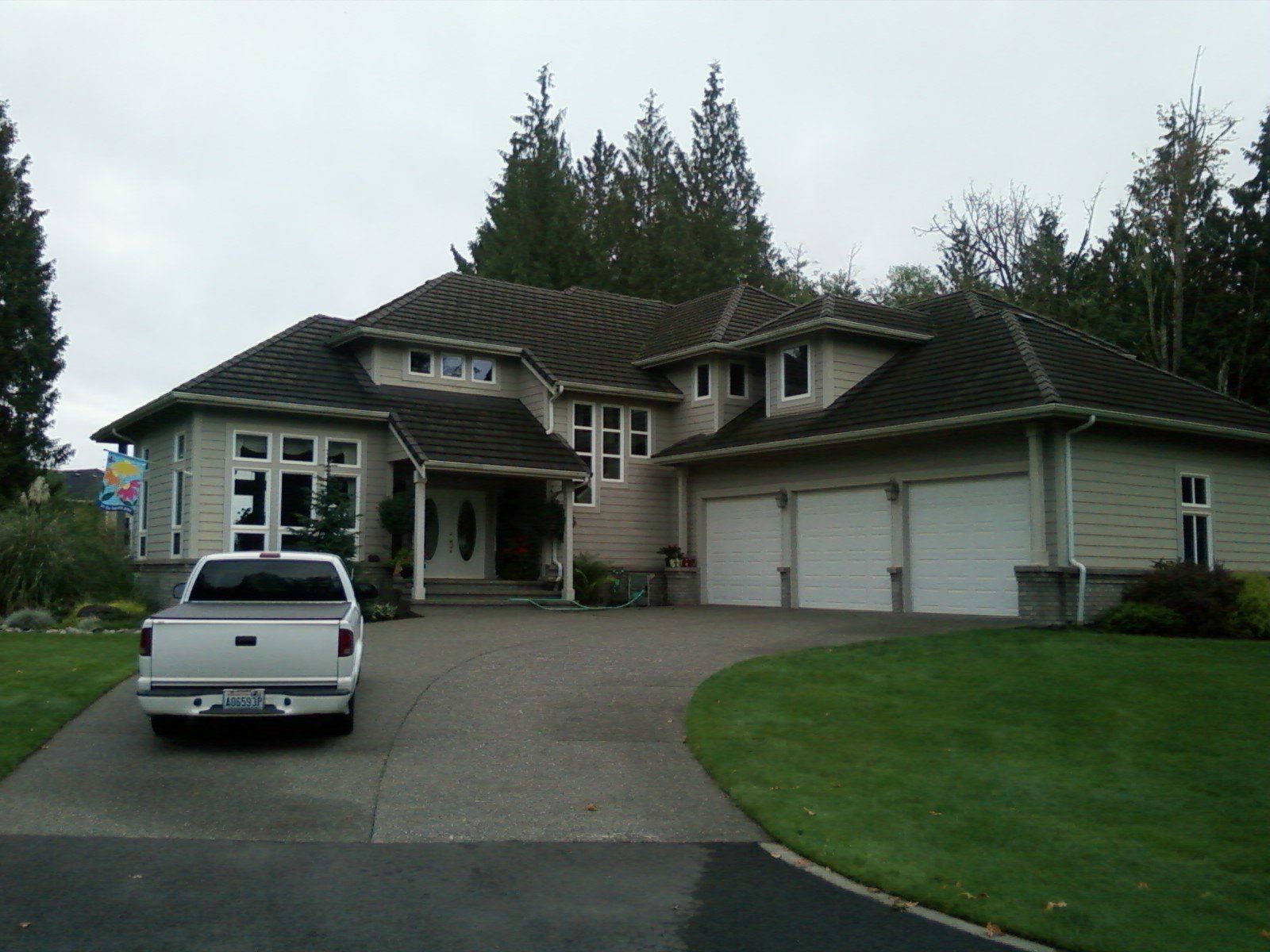A white truck is parked in front of a large house