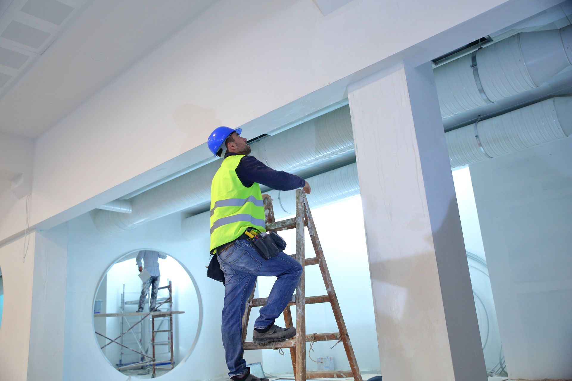 A man is standing on a ladder in a room.