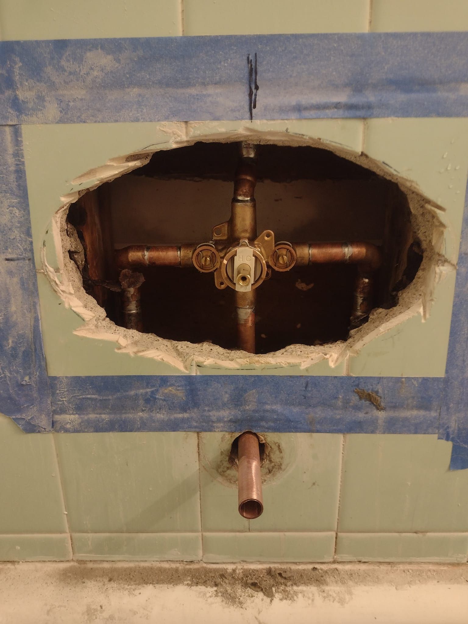 A hole in a wall with a copper pipe in it