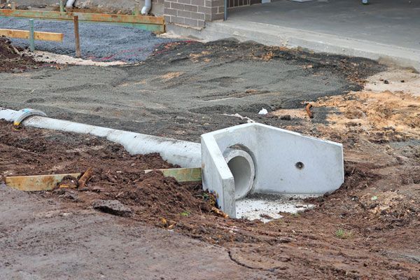 A concrete pipe is laying in the dirt on the side of the road.