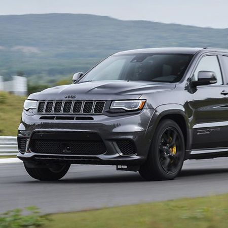 A gray jeep grand cherokee is driving down a road.