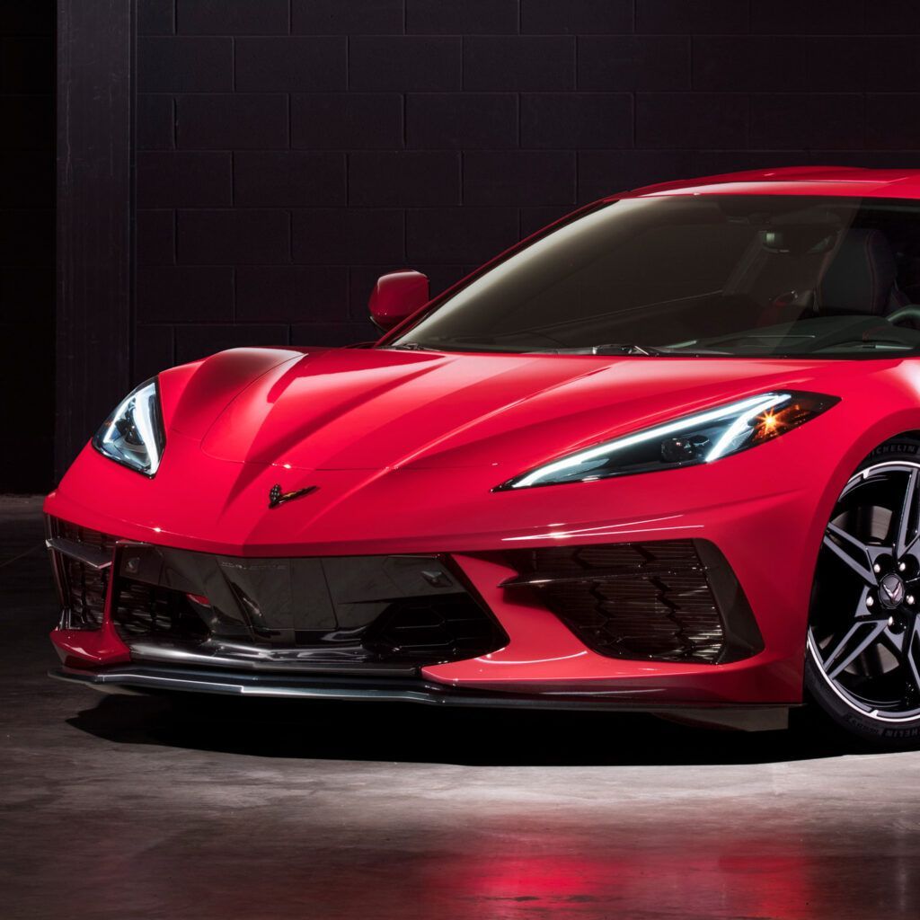 A red sports car is parked in a dark room
