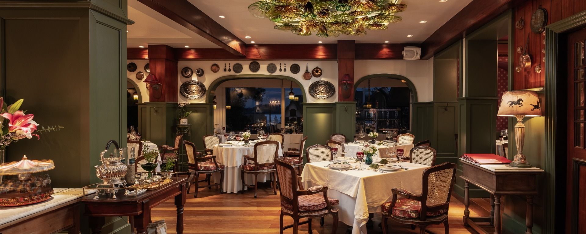 Sala de jantar elegante de restaurante com mesas postas, iluminação aconchegante e decoração festiva de fim de ano.