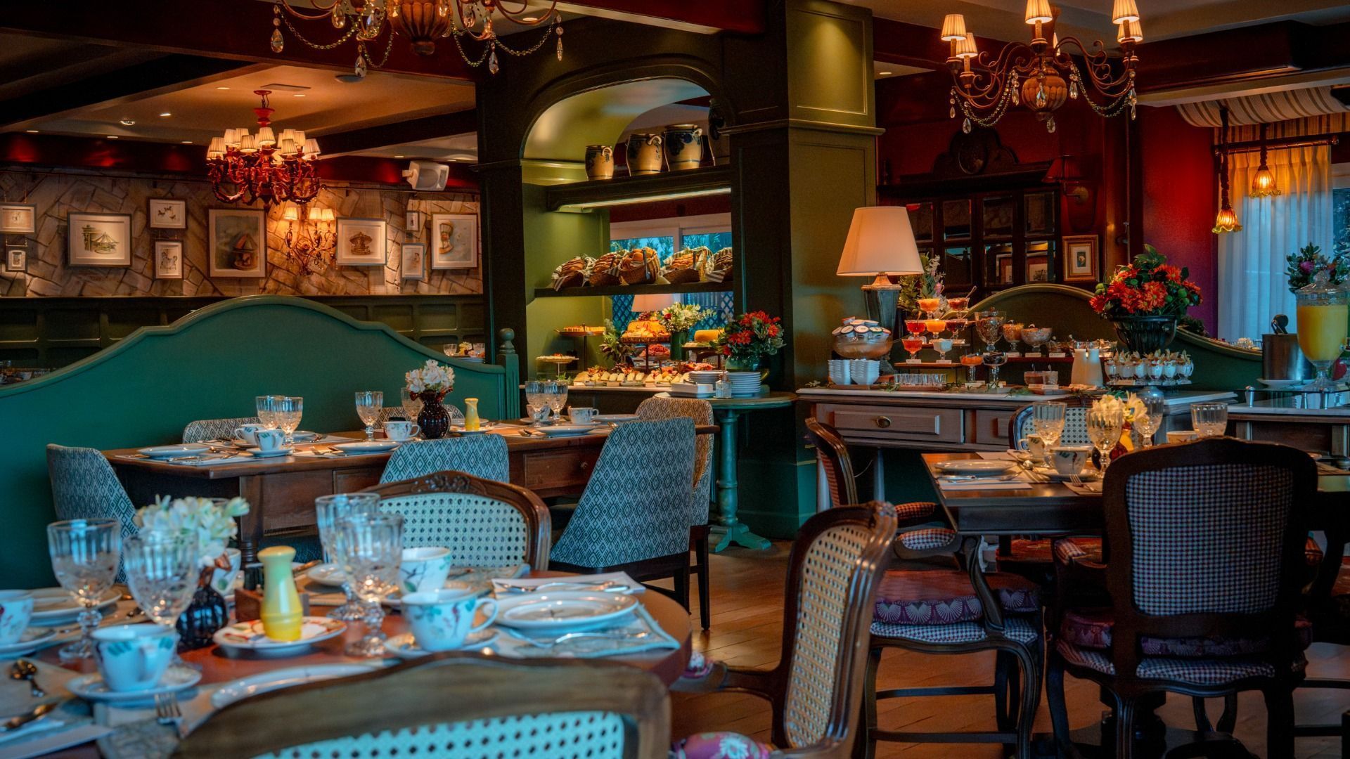 Sala de jantar aconchegante do restaurante com bancos estofados em tom azul-petróleo, mesas postas, iluminação acolhedora e um aquário em exposição.
