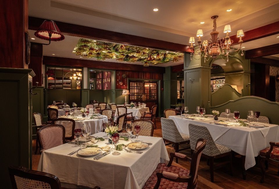Sala de jantar elegante do restaurante com mesas cobertas com toalhas brancas, lustres e iluminação ambiente aconchegante.