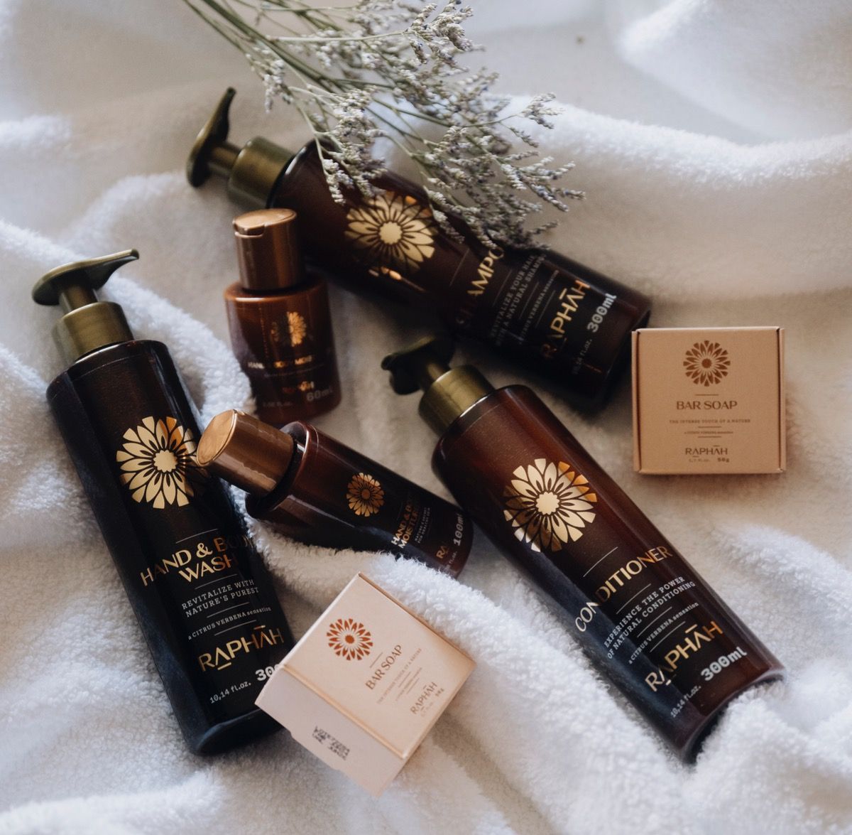 Diversos frascos de produtos para cuidados com a pele e caixas de cremes em tons de preto e âmbar sobre uma toalha branca.