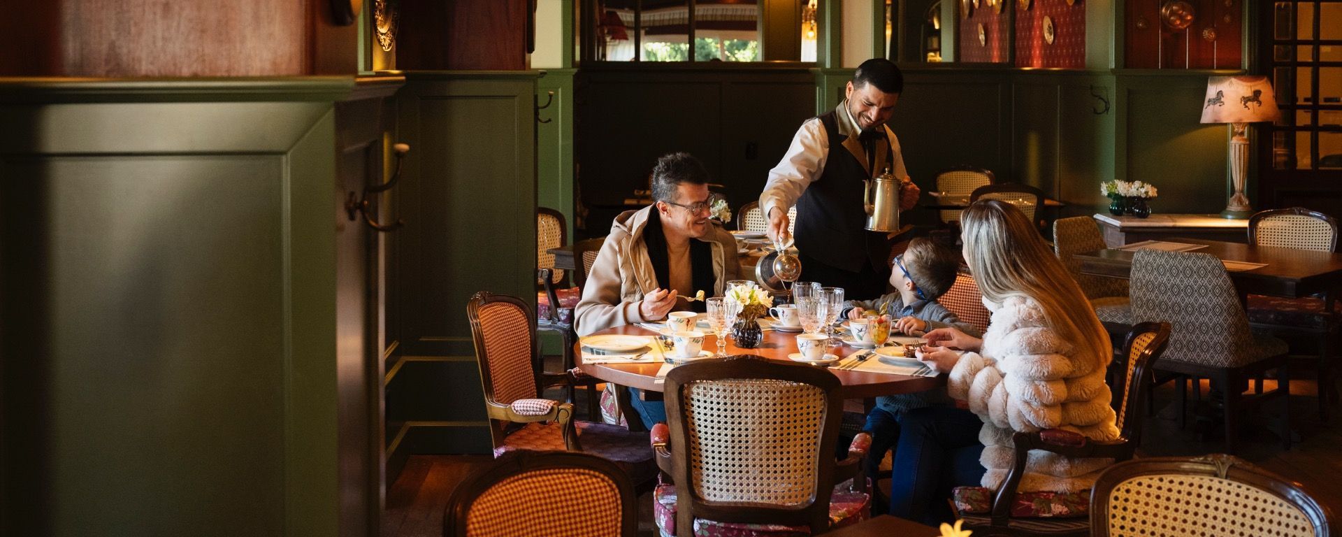 Pessoas jantando e conversando em uma mesa de restaurante com iluminação aconchegante, com bebidas e pratos à disposição.