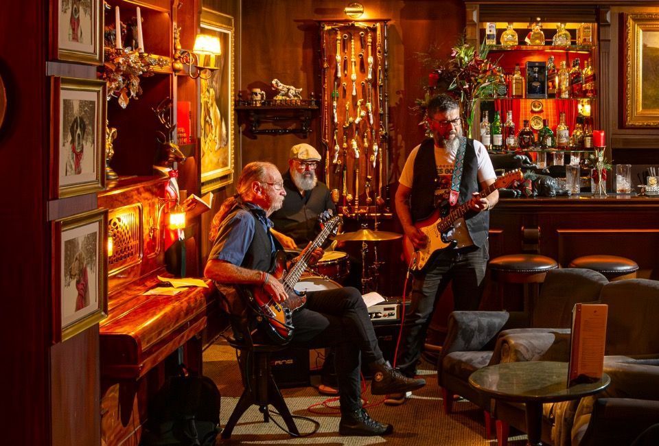 Dois músicos se apresentando em um bar aconchegante, com iluminação suave em tons de laranja.