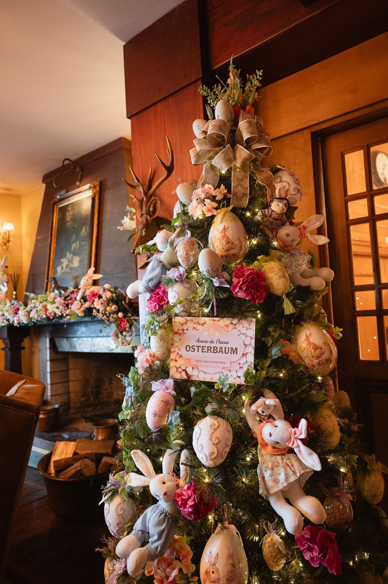 Árvore de Natal decorada com flores e enfeites em uma sala aconchegante perto da lareira.