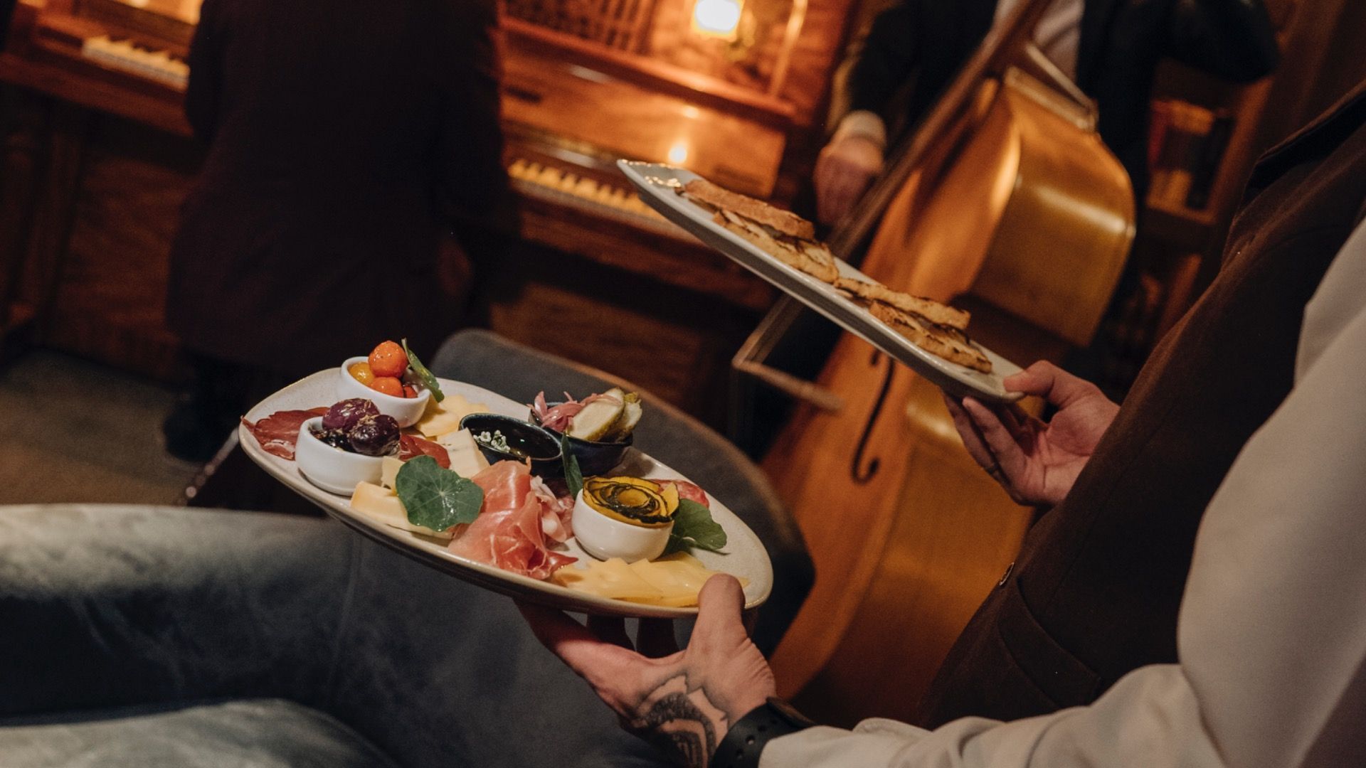 Sushi servido em pratos individuais em um restaurante com iluminação aconchegante, com uma pessoa lendo o cardápio ao lado da mesa.