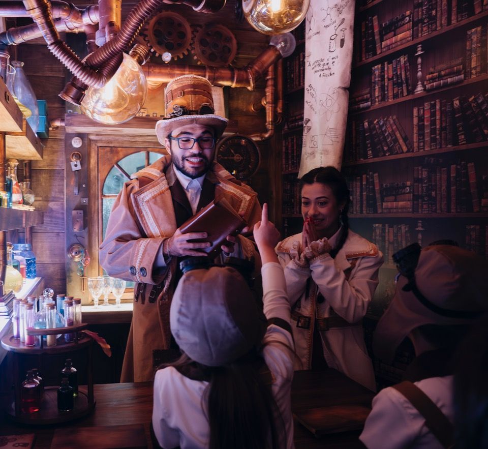 Duas pessoas conversando em um bar aconchegante, iluminado por lanternas, com estantes de livros e luz âmbar quente.