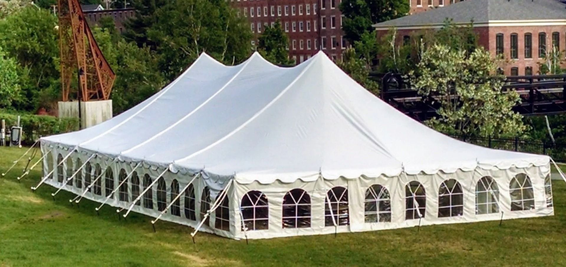 Large white event tent on a grassy lawn with arched windows and peaked canopies