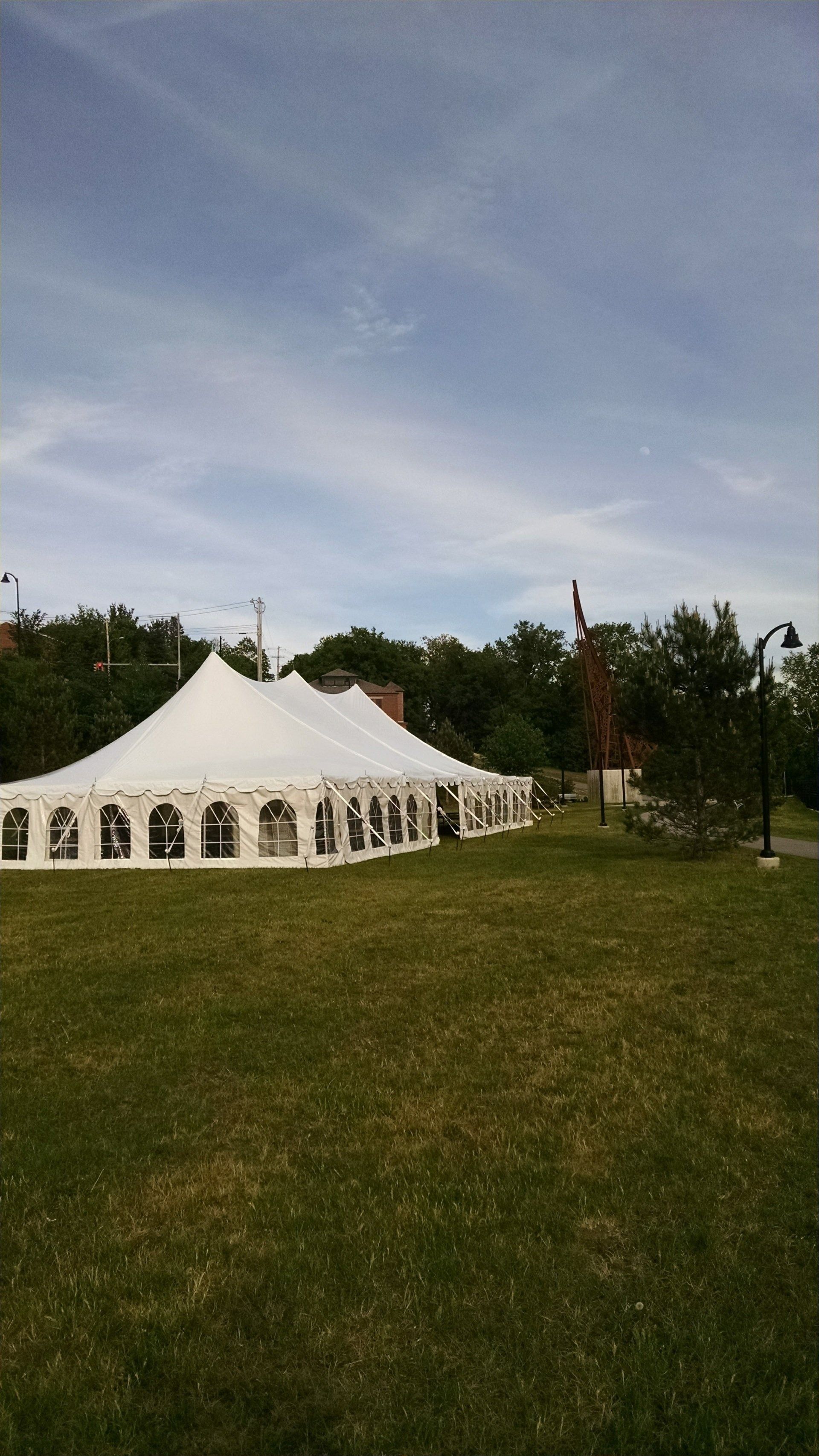White event tent on a grassy field under a partly cloudy sky