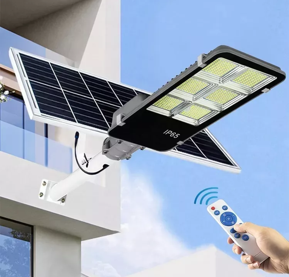 Una mano sostiene un control remoto apuntando a una farola LED solar con clasificación IP65 instalada en el exterior de un edificio.