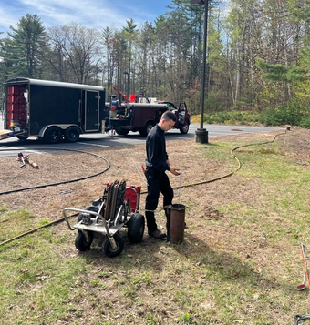Man near a machine performing some type of construction or maintenance work.