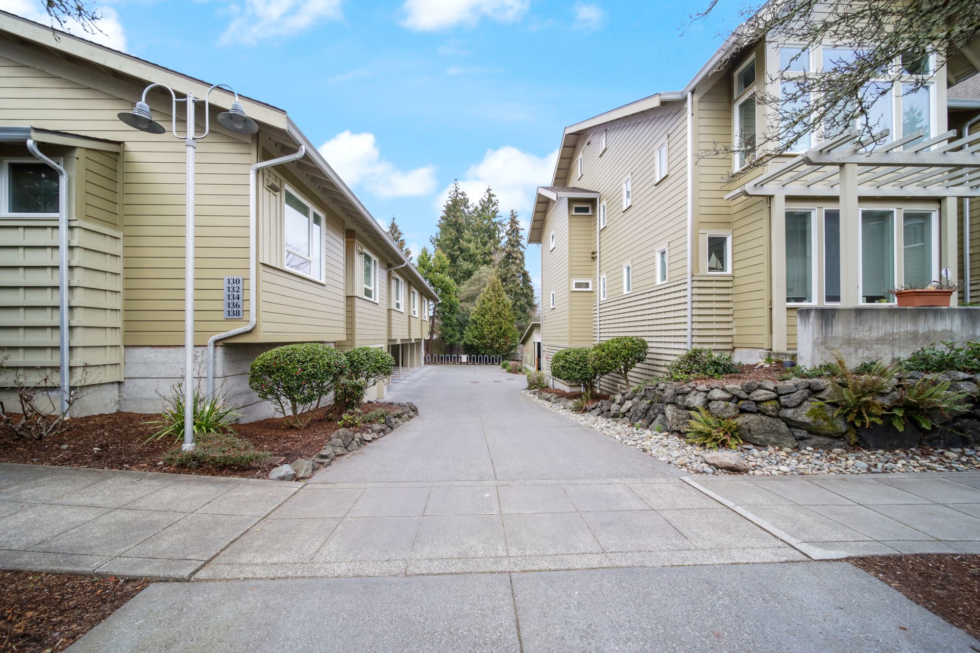 Courtyard walkway between beige townhouses with blue sky overhead