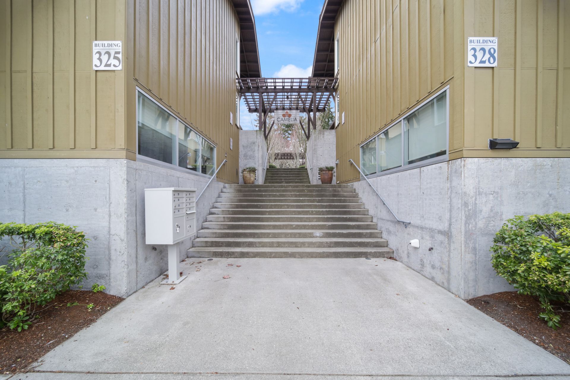 Concrete stairway between two tan buildings with unit numbers 325 and 328, leading to a walkway above.