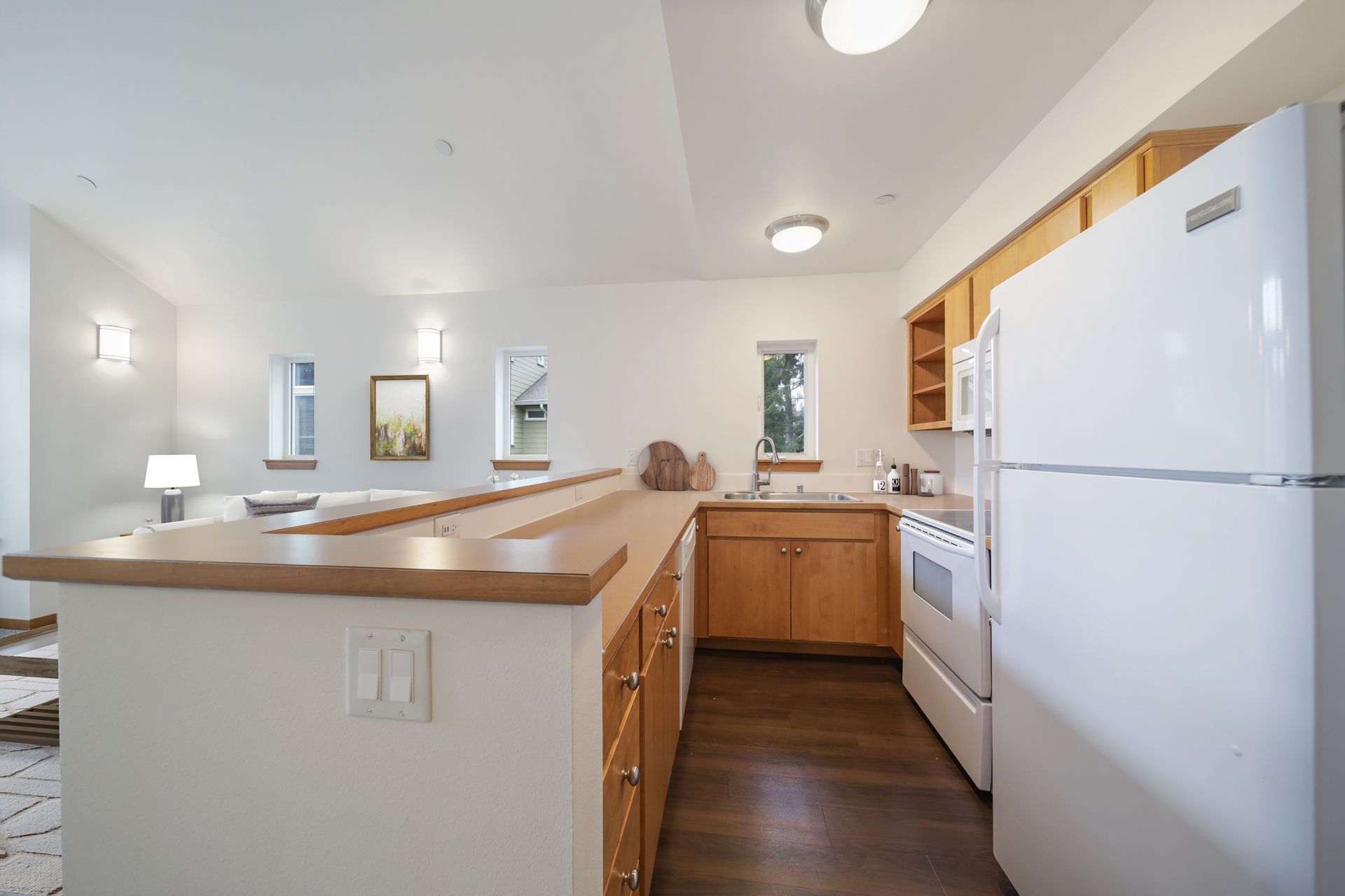 Bright kitchen with white appliances, wood cabinets, and a breakfast bar.