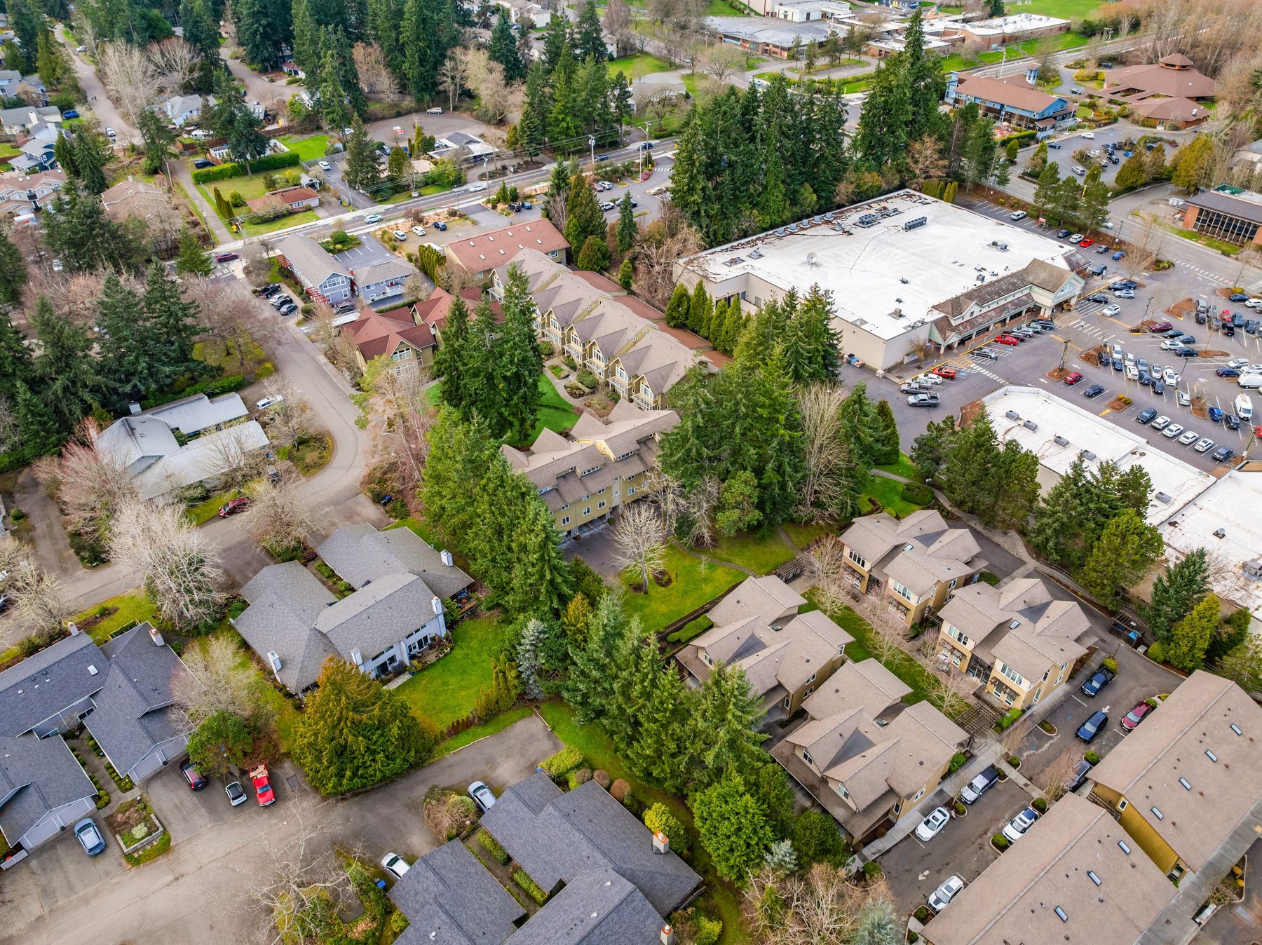 Aerial view of a suburban neighborhood with apartment buildings, trees, and a parking lot nearby.