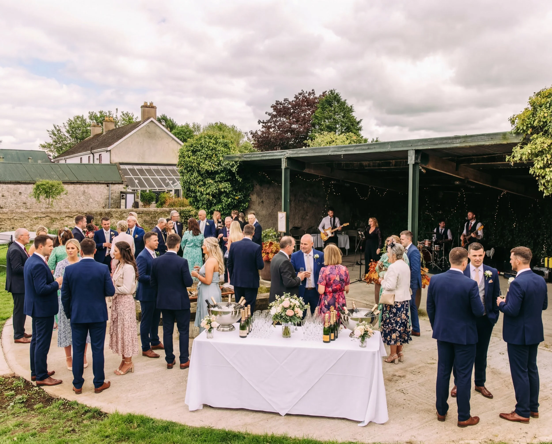 Outdoor garden reception with guests mingling around a catered table under a canopy
