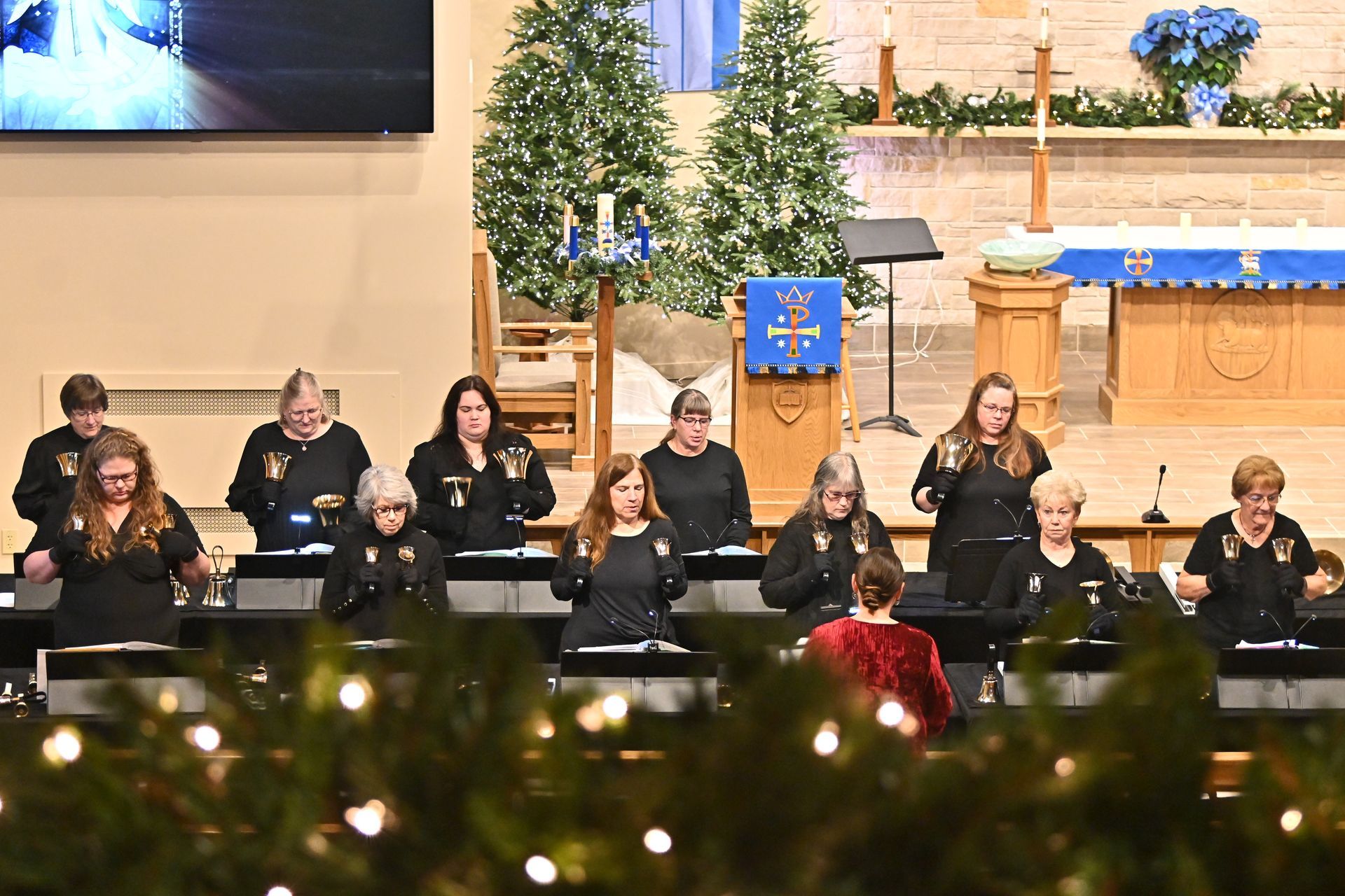 Choir performing in a church, with a decorated altar and Christmas trees in the background