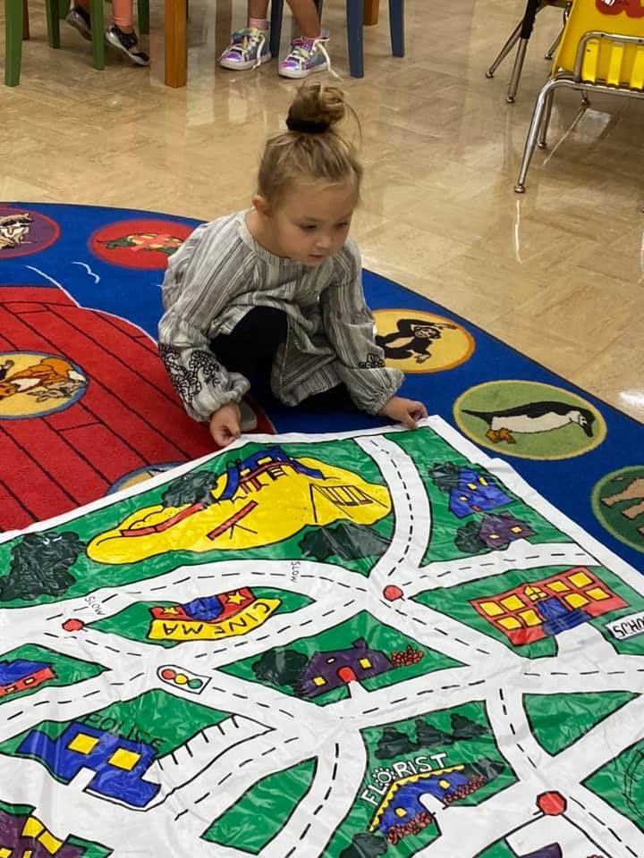 Child sitting on a colorful classroom play mat with a road map design