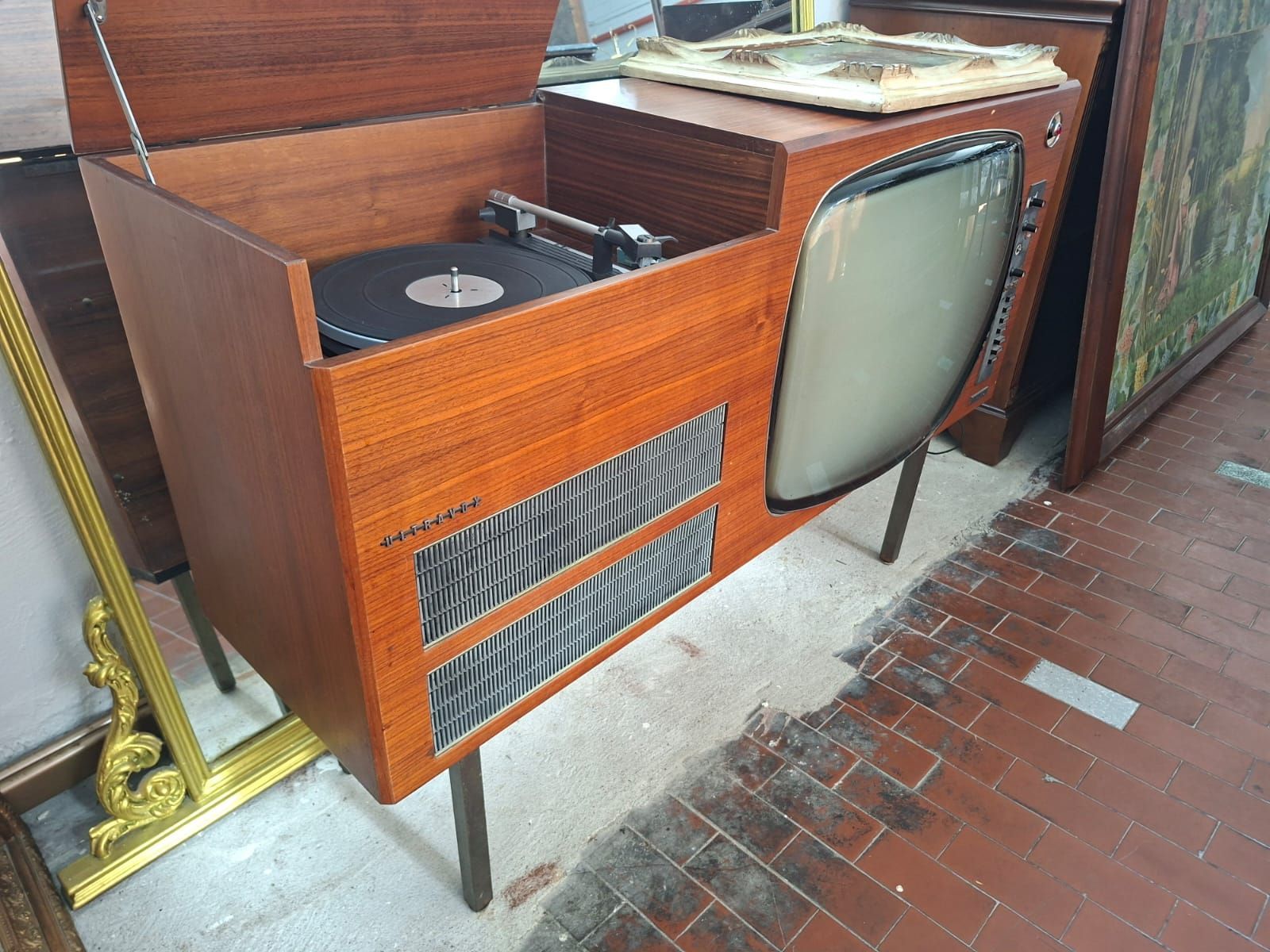 Una consolle vintage in legno in stile moderno di metà secolo, con televisore integrato e vano a giorno per il giradischi.