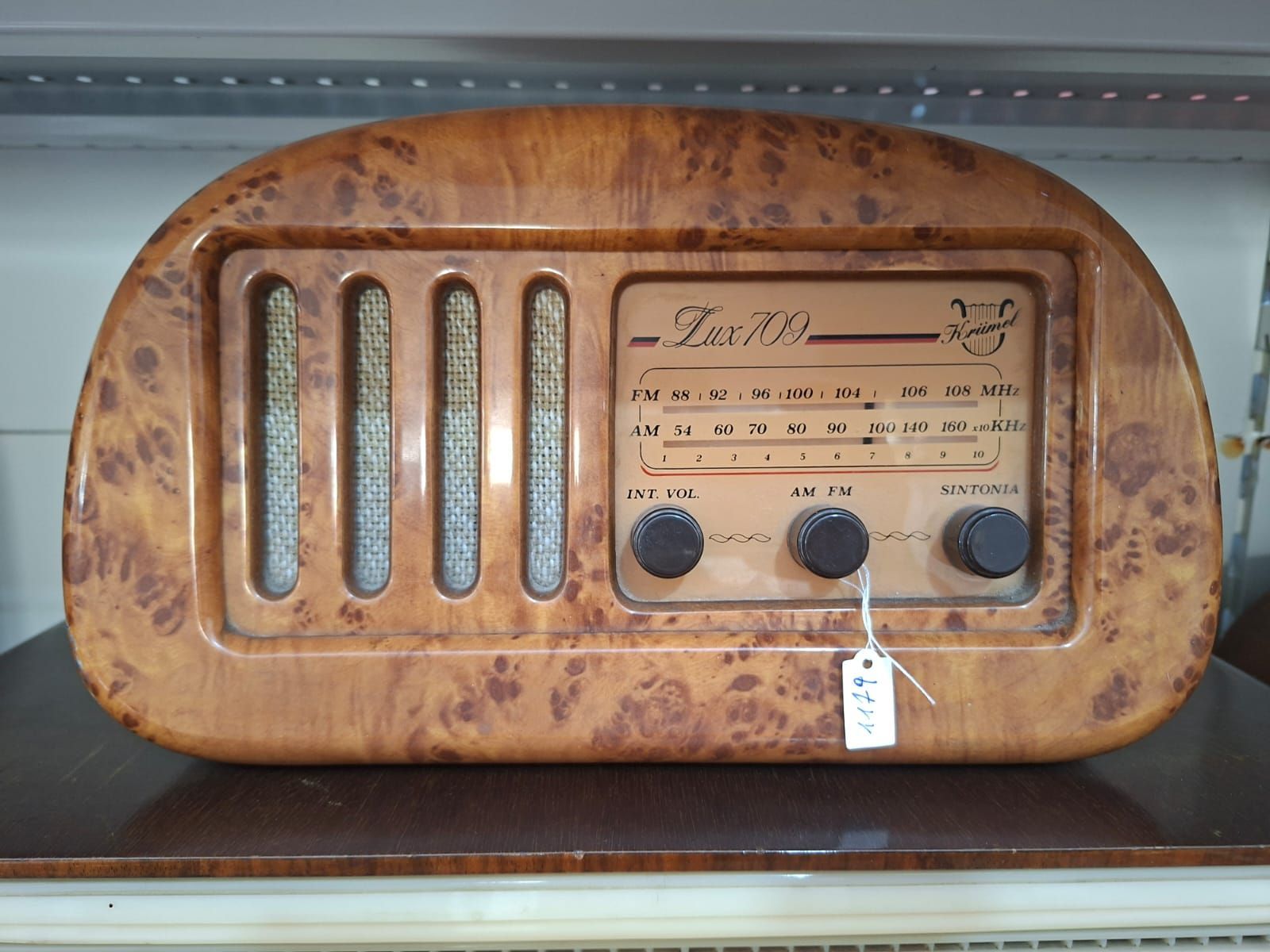 Una radio vintage in legno con impiallacciatura in radica, quadrante color cuoio con il marchio