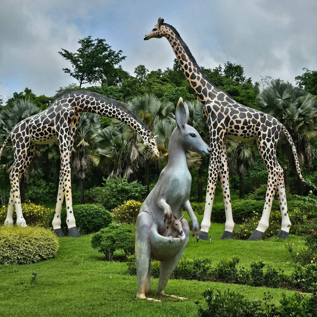 A statue of a kangaroo standing next to two giraffes