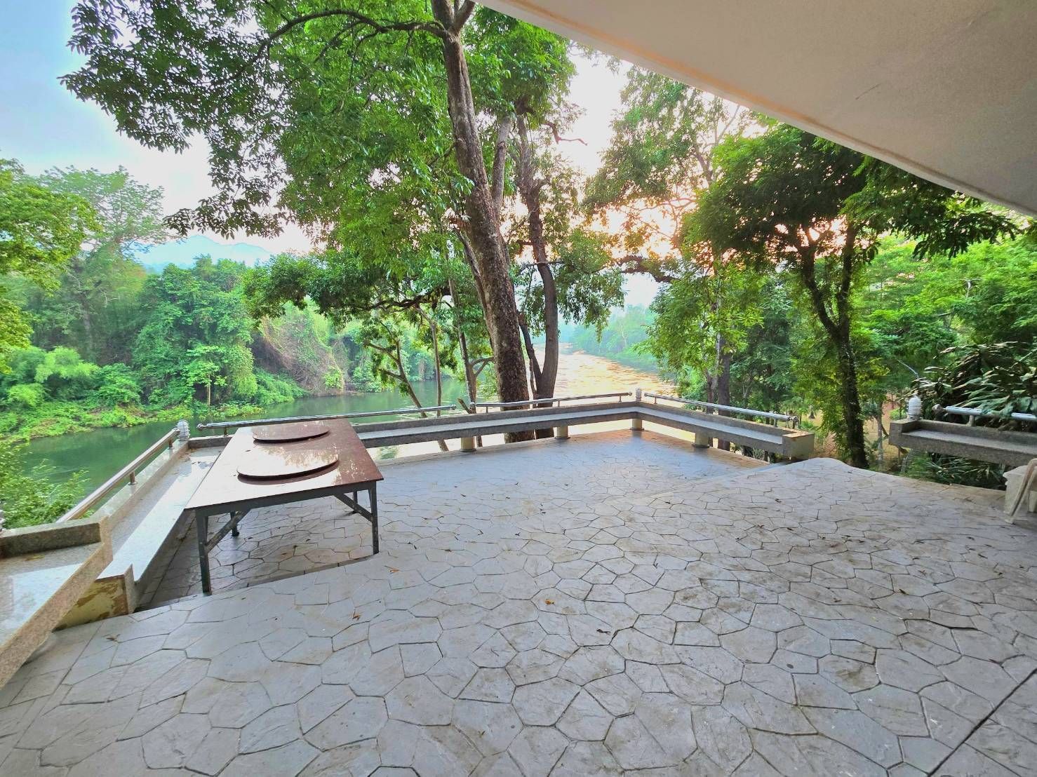 A patio with a table and benches overlooking a river.