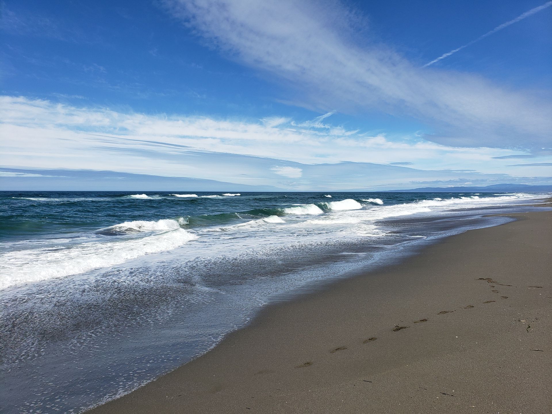 A beach with waves coming in on a sunny day