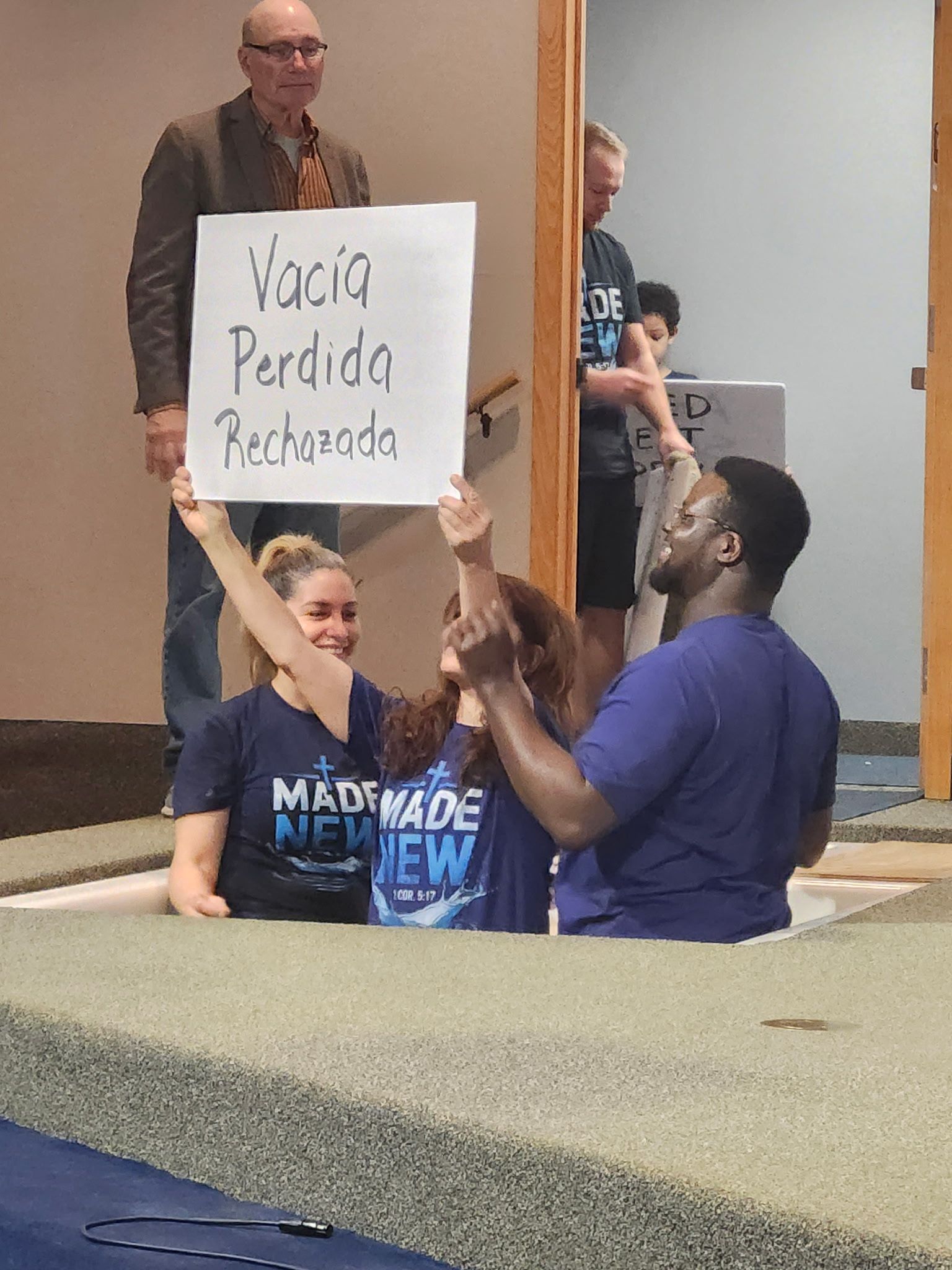 Protester holds a sign reading “Vota Perdida” while seated demonstrators raise fists indoors.
