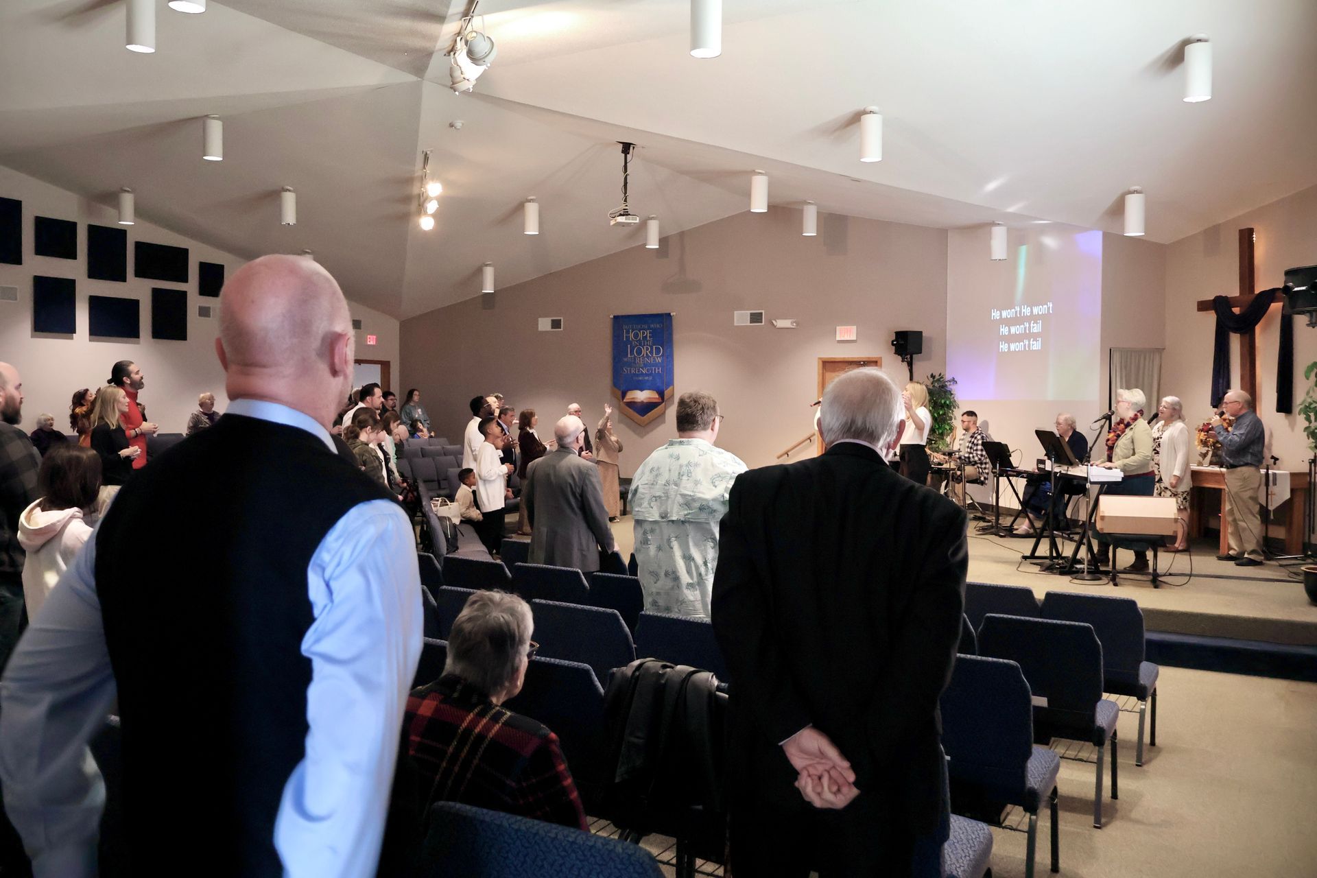 People gathered in a church hall during a service, with an altar and cross at the front.