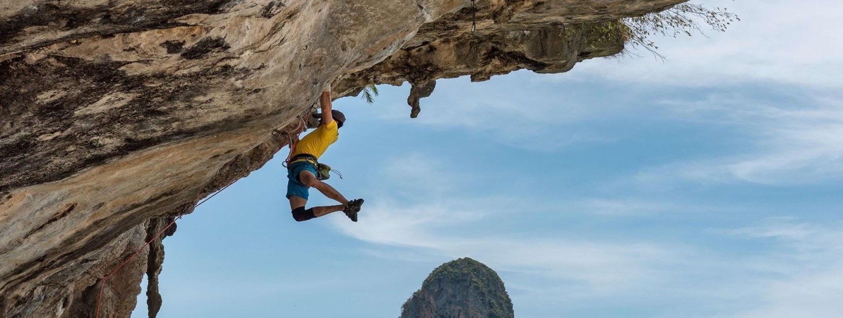 A man is climbing up the side of a cliff.