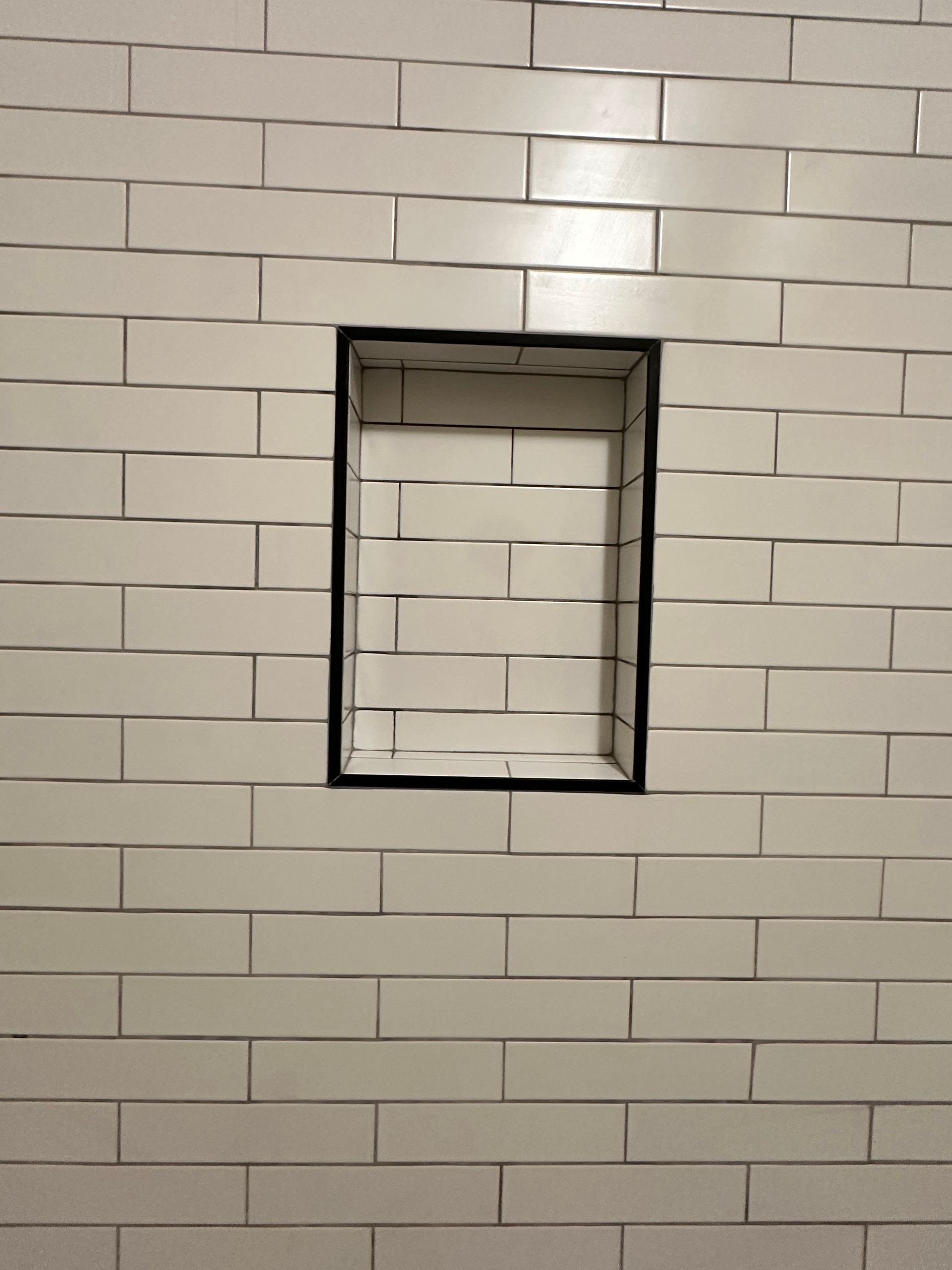 A white brick wall with a niche in the middle of it.
