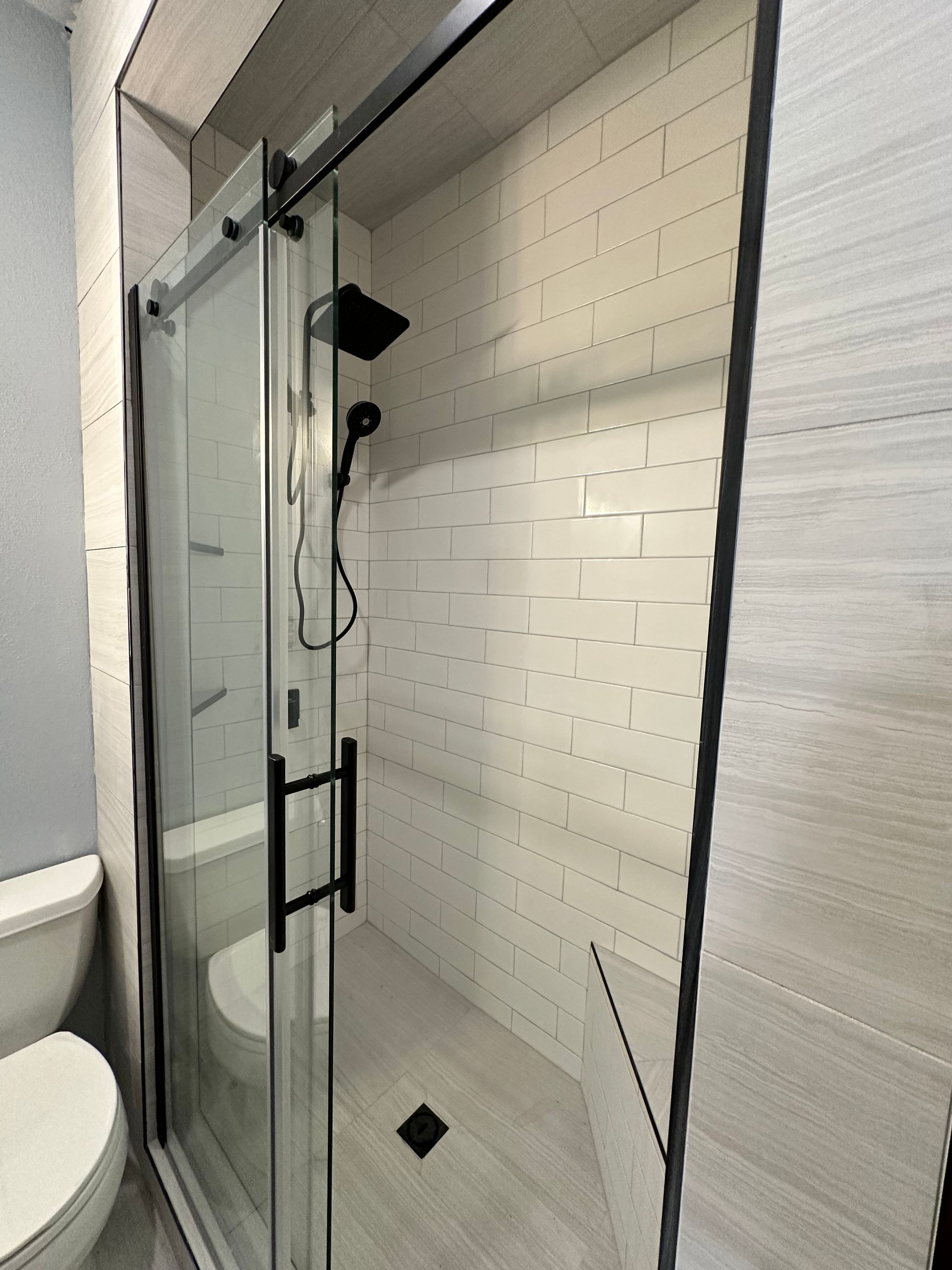 A bathroom with a toilet and a shower with a sliding glass door
