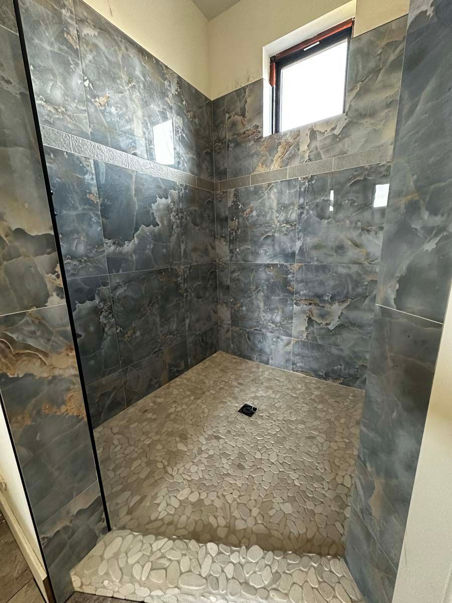 A walk in shower with tiled walls and a window.