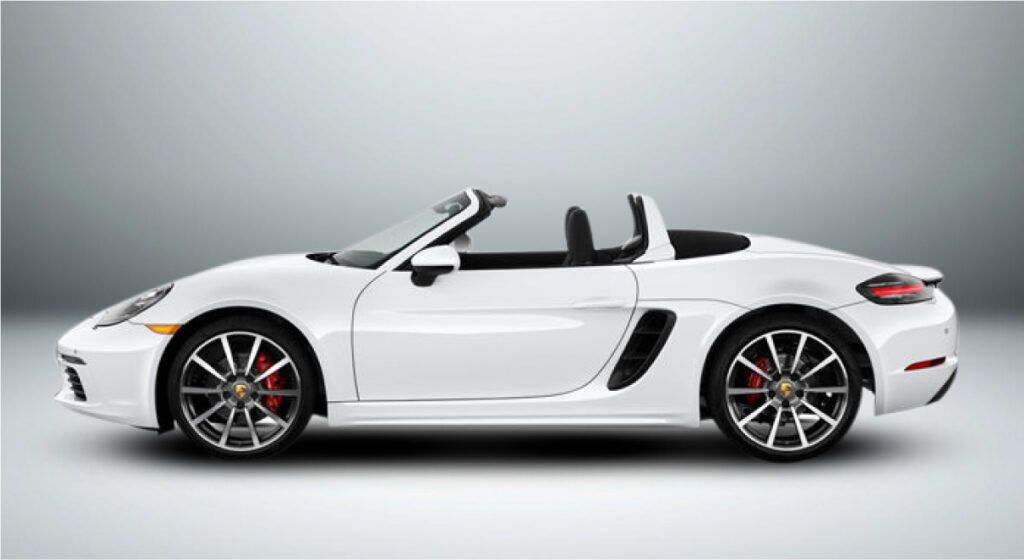 Um porsche boxster conversível branco com a capota voltada para baixo sobre um fundo branco.
